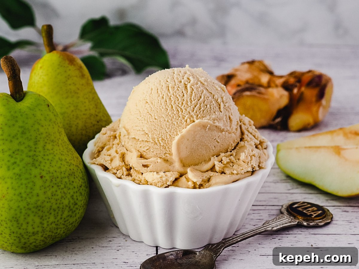 Scoop of pear ice cream with spoon, fresh pears and fresh ginger on the side.