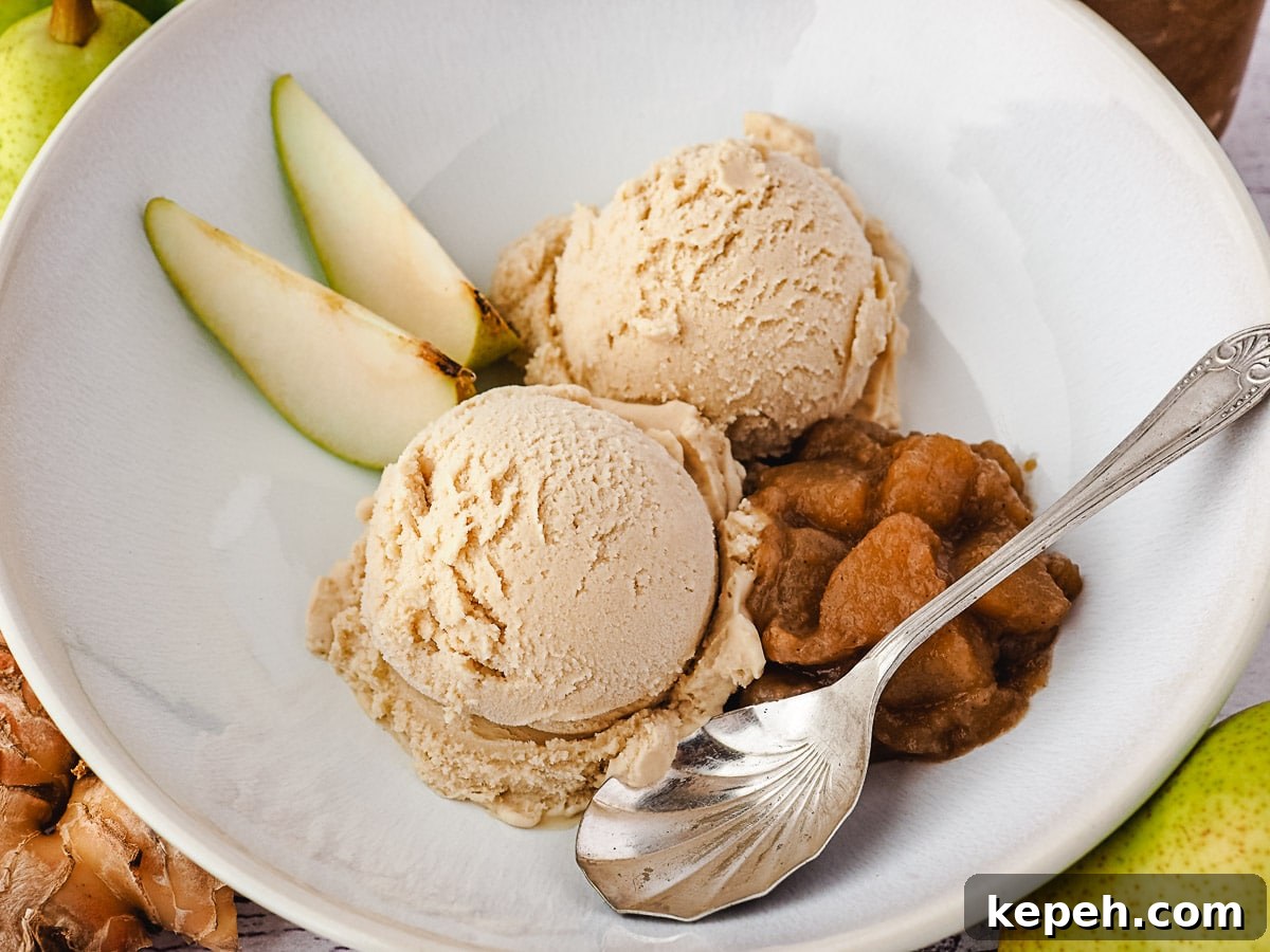 Serving of scoops of pear ice cream in a bowl, with fresh pears, pear compote and a spoon.