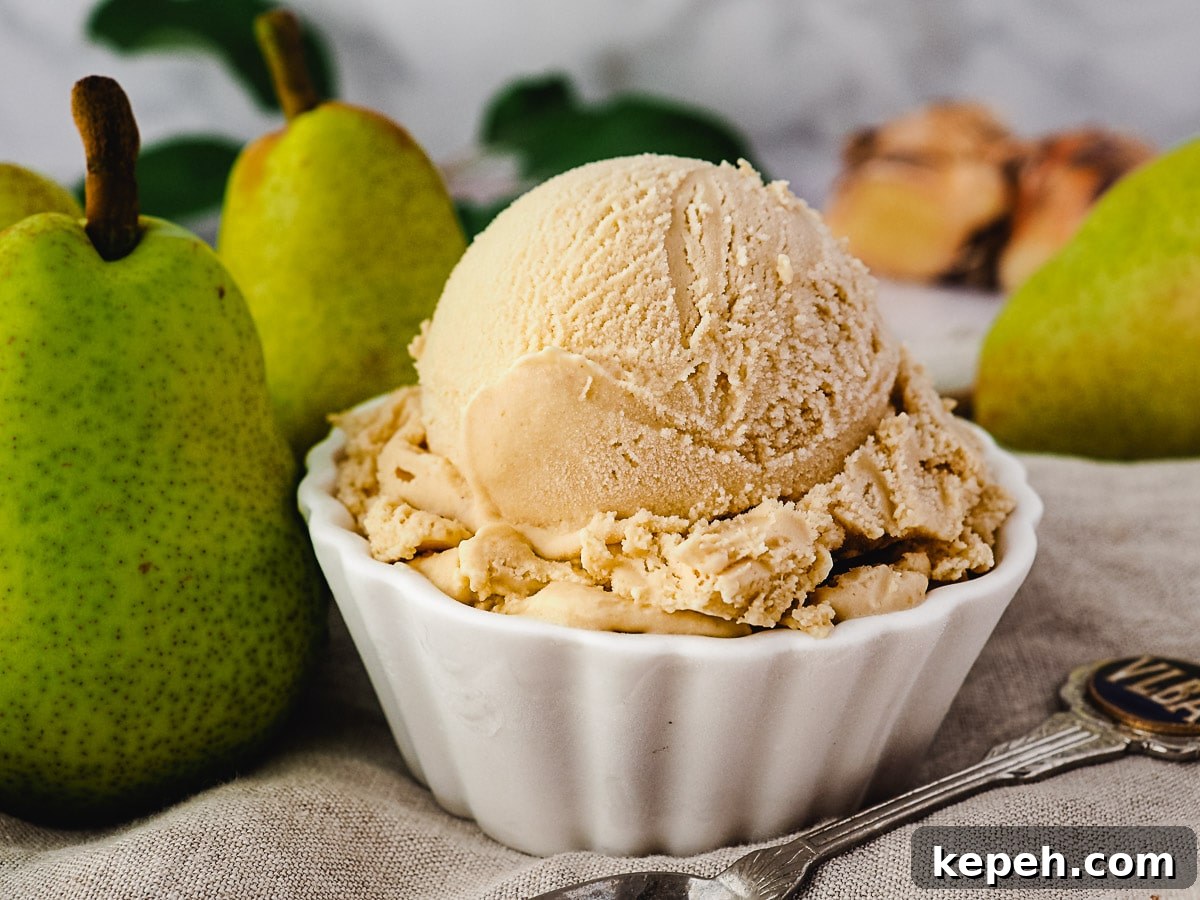 Scoop of pear ice cream with spoon, fresh pears and fresh ginger on the side.