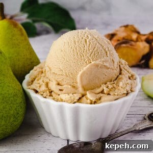 Scoop of pear ice cream with spoon, fresh pears and fresh ginger on the side.
