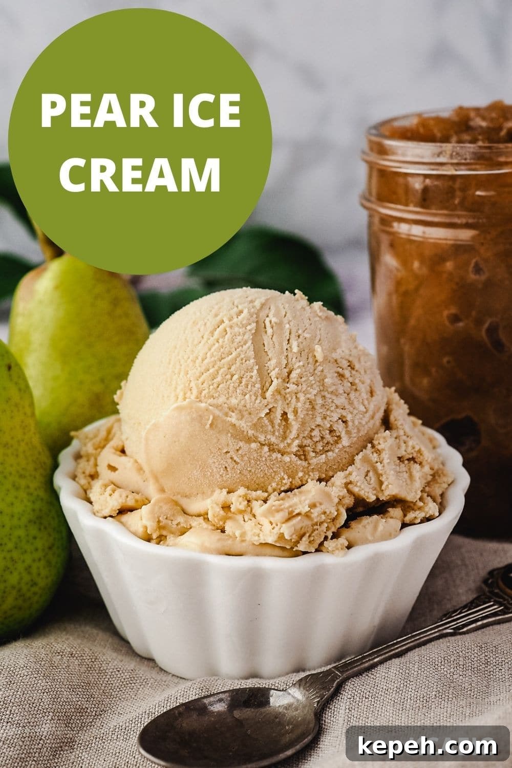 Scoop of pear ice cream with spoon, fresh pears and jar of pear compote on the side.