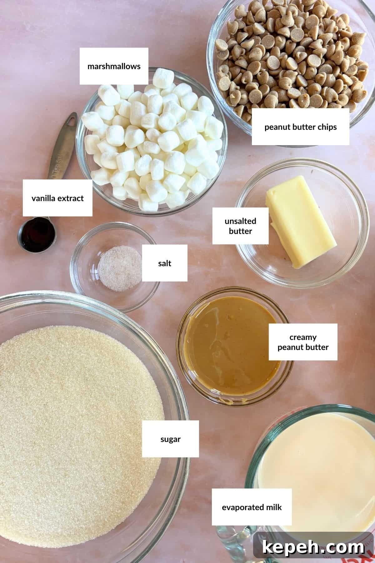 Decadent Peanut Butter Fudge Recipe You'll Love 3 Bowls of labeled ingredients for an easy peanut butter fudge recipe, including marshmallows, peanut butter chips, vanilla extract, salt, unsalted butter, creamy peanut butter, sugar, and evaporated milk.