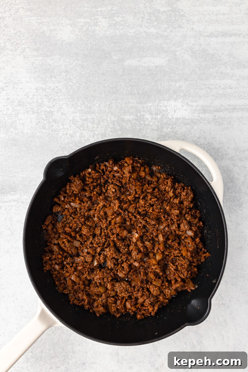 Black beans, tomatoes and enchilada sauce are stirred into the ground beef mixture.