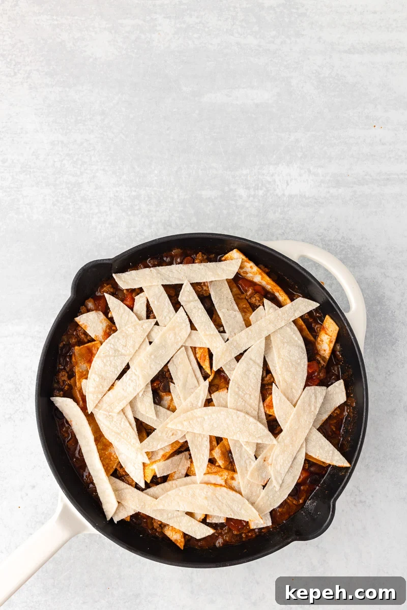 Strips of corn tortillas are place onto of, then stireed into the ground beef mixture.