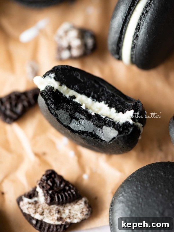 Robin's Egg Macarons: Delicate Blue Pastry Recipe and Tips 13 Half eaten oreo macaron on parchment paper surrounded by oreo macarons and broken pieces of oreo cookies.