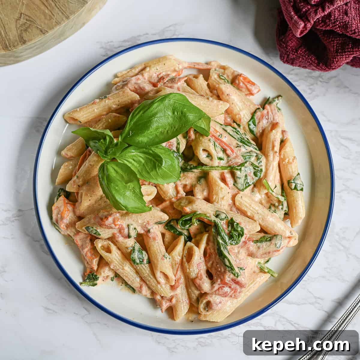 Creamy Boursin Pasta with Garlic and Herbs 2 boursin cheese pasta on a plate, topped with sprig of basil.