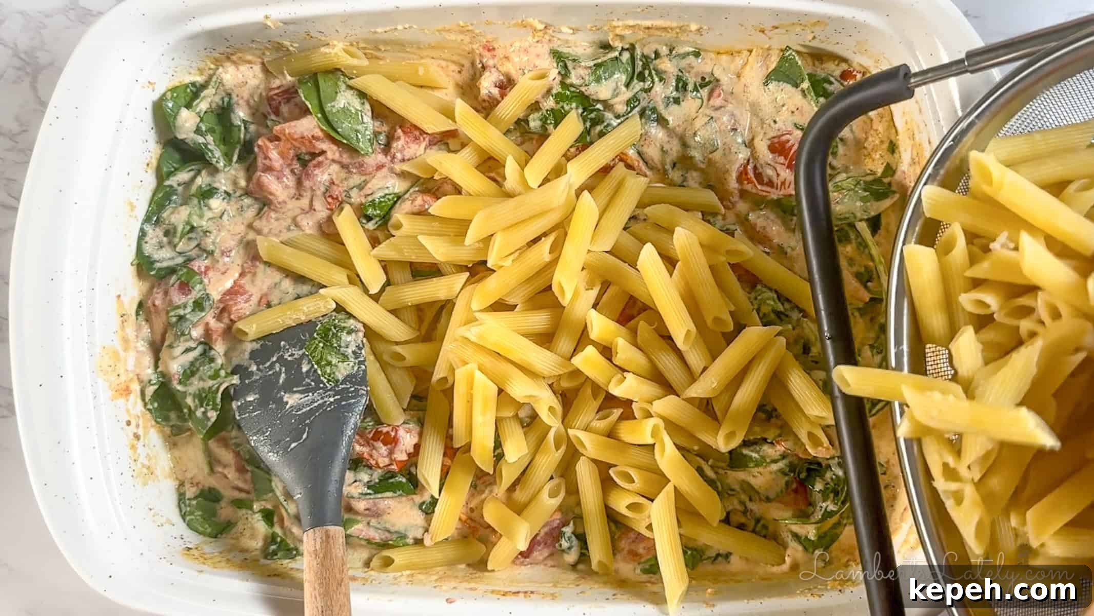 Creamy Boursin Pasta with Garlic and Herbs 7 adding pasta to the boursin tomato cheese sauce in a baking dish.