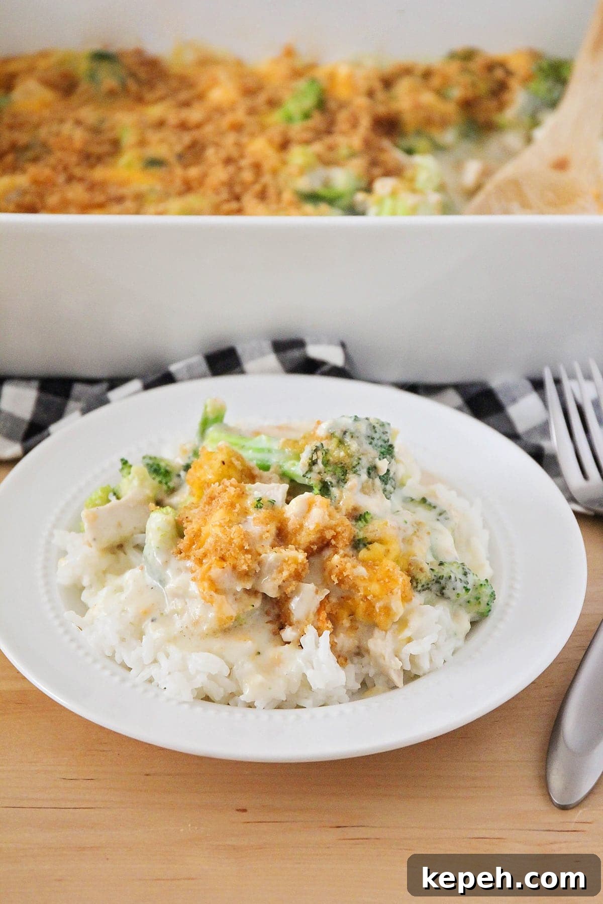 Easy Chicken Divan is loaded with chunks of tender chicken and broccoli and smothered in a cream sauce. It is perfect to freeze for later! Chicken Divan served on rice on a white plate.