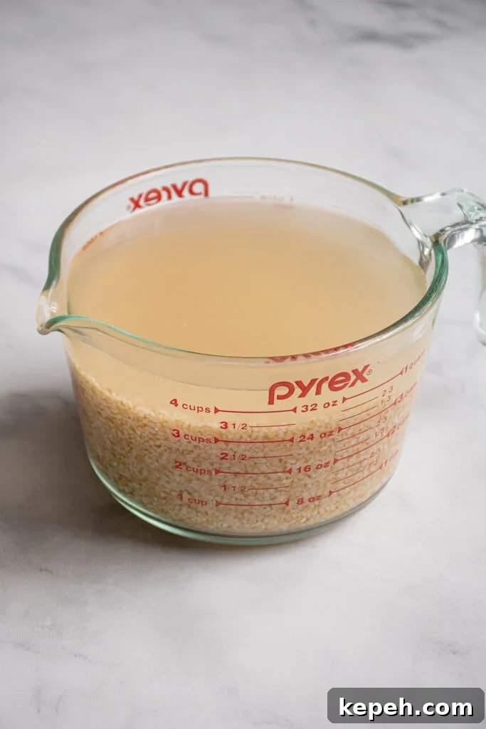 Large glass measuring cup filled with soaking bulgur and water.
