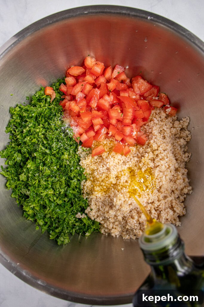A large mixing bowl filled with the ingredients for tabbouleh not yet mixed while olive oil is being drizzled on to them.
