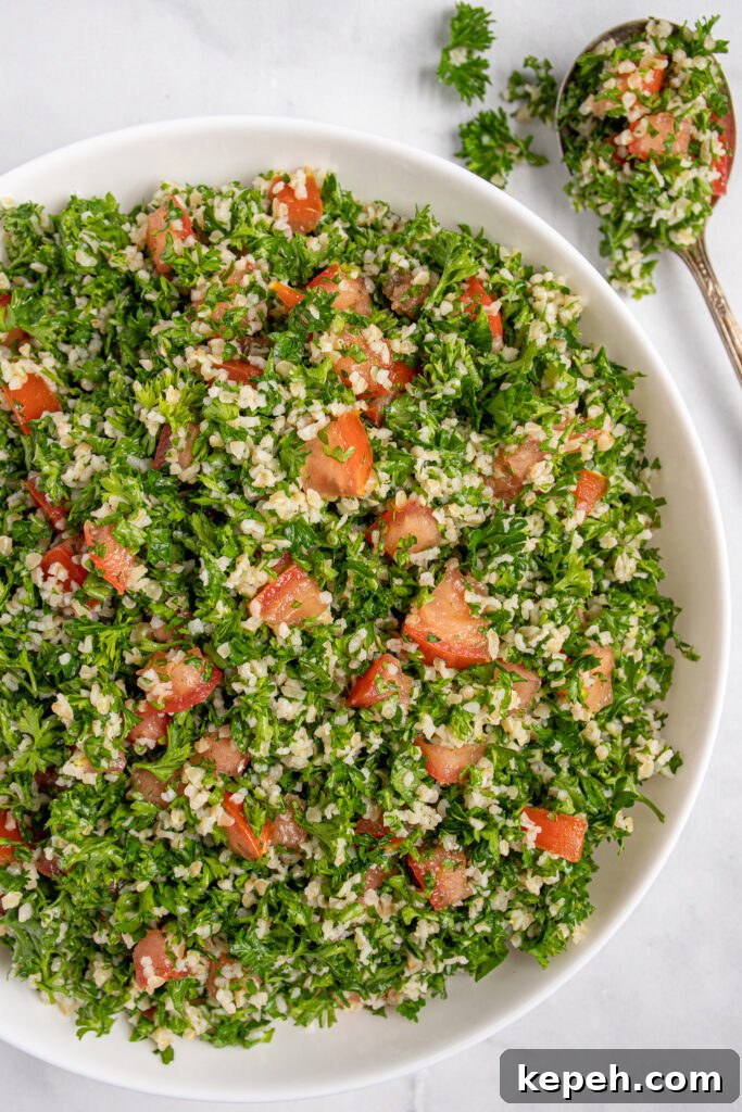 Close up view of tabbouleh salad recipe in a bowl showing off parsley, tomatoes, and bulgur.