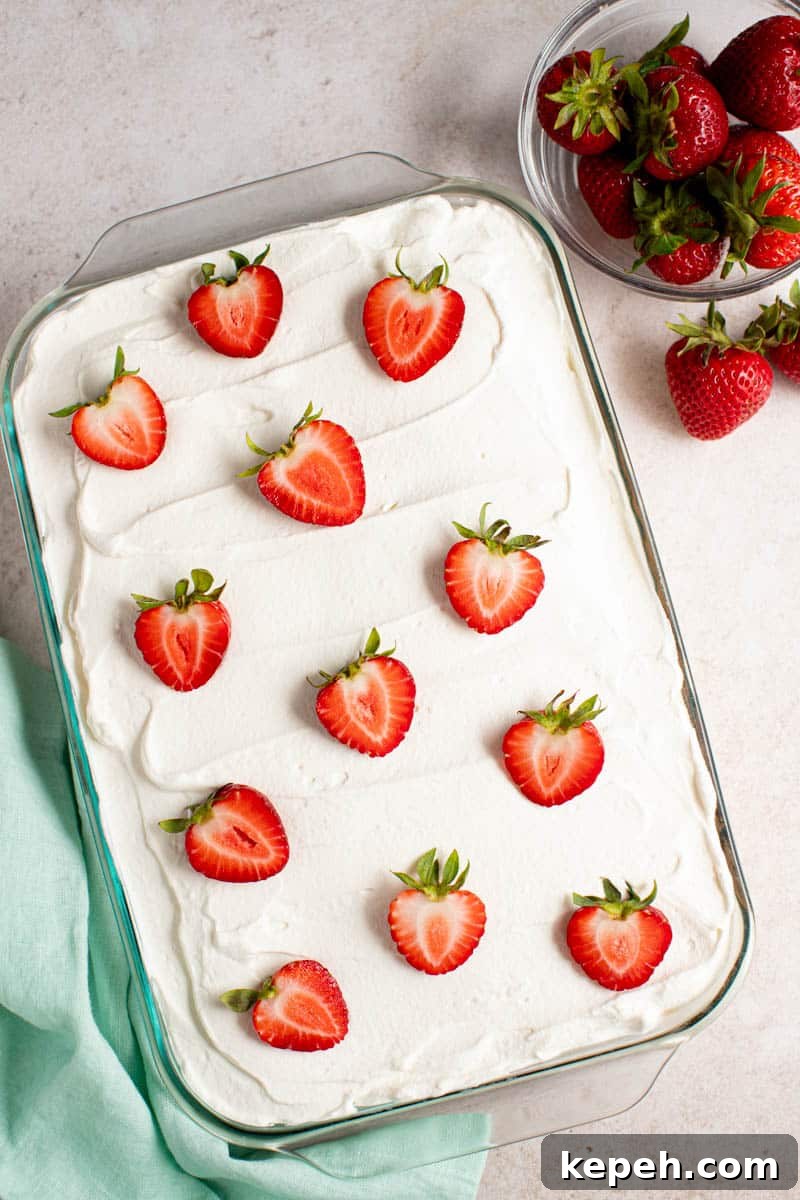 Strawberry Tres Leches Cake Recipe — Moist Milk-Soaked Dessert 5 a whole strawberry tres leches cake on a counter for serving.