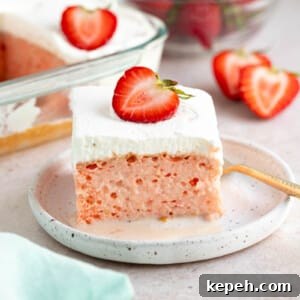 Strawberry Tres Leches Cake Recipe — Moist Milk-Soaked Dessert 6 A slice of strawberry tres leches cake on a white plate for serving. Sliced strawberries and a bowl of strawberries sits to the site on a countertop.