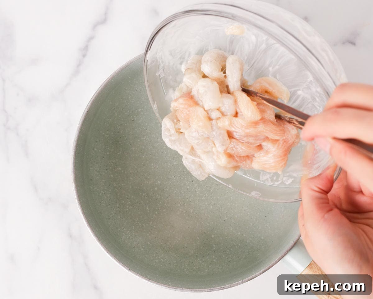Adding marinated shrimps and chicken to a pot of hot water.