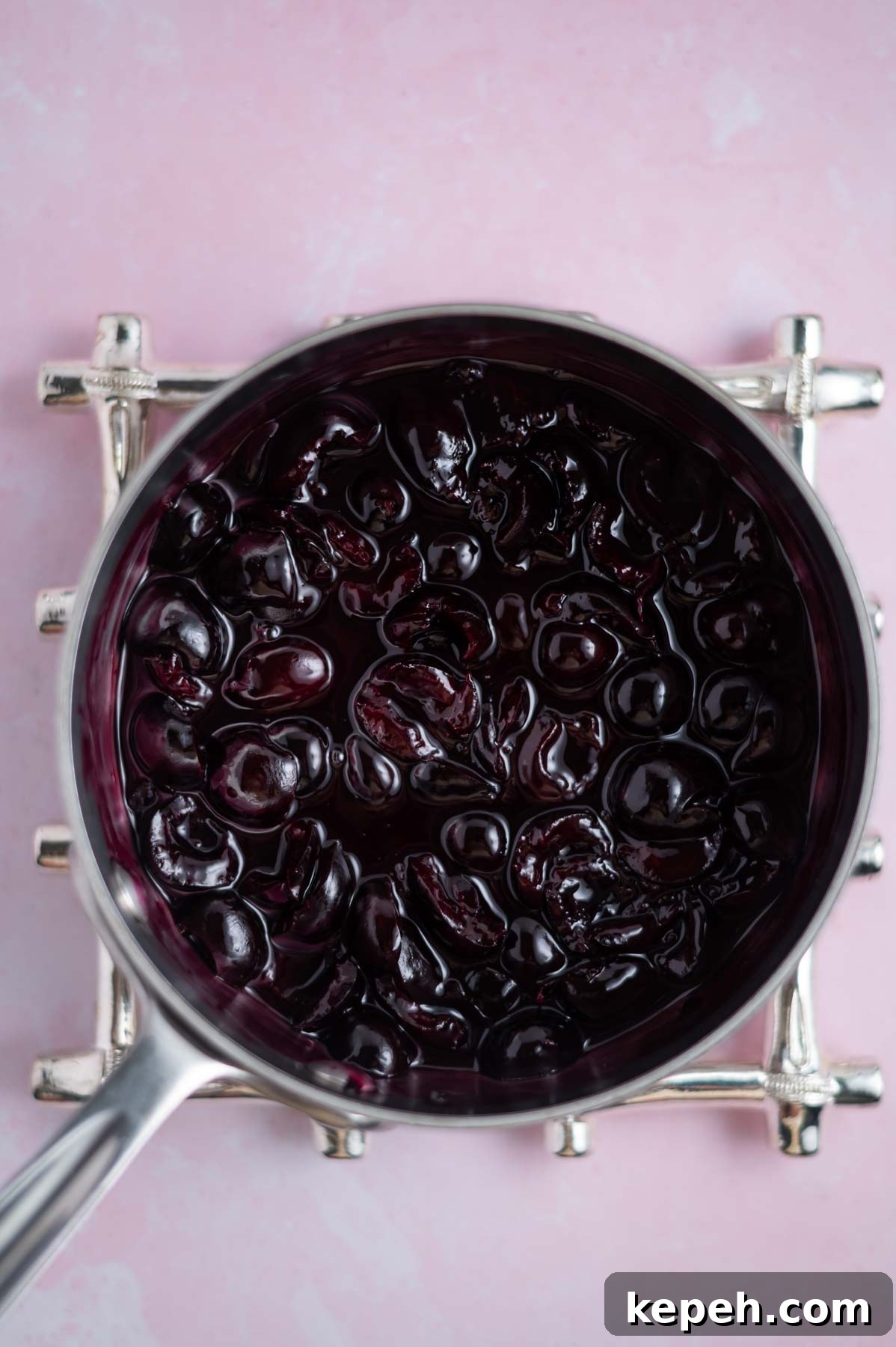 Light and Fluffy White Forest Cake Recipe 12 cherry filling in a saucepan on a trivet