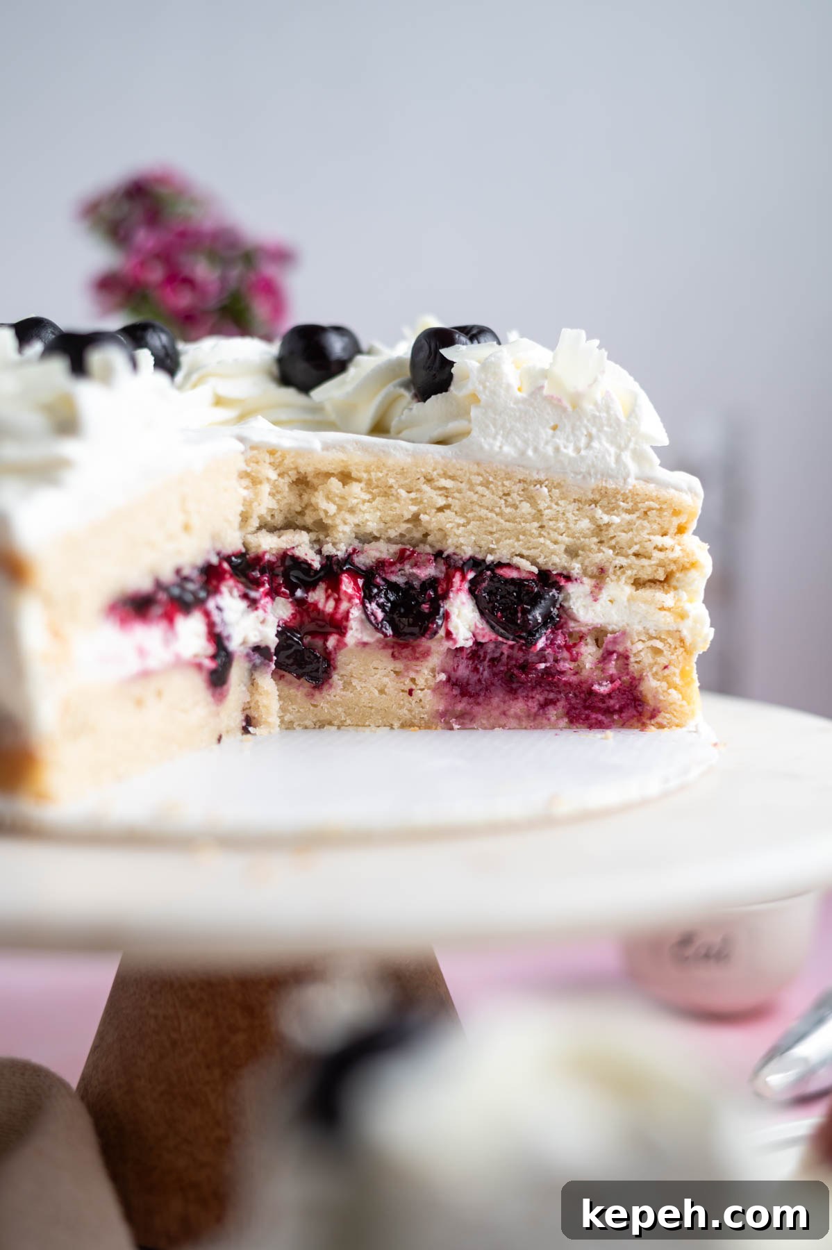 Light and Fluffy White Forest Cake Recipe 3 white forest cake on a cake stand showing an inside look at the cherry filling in the middle