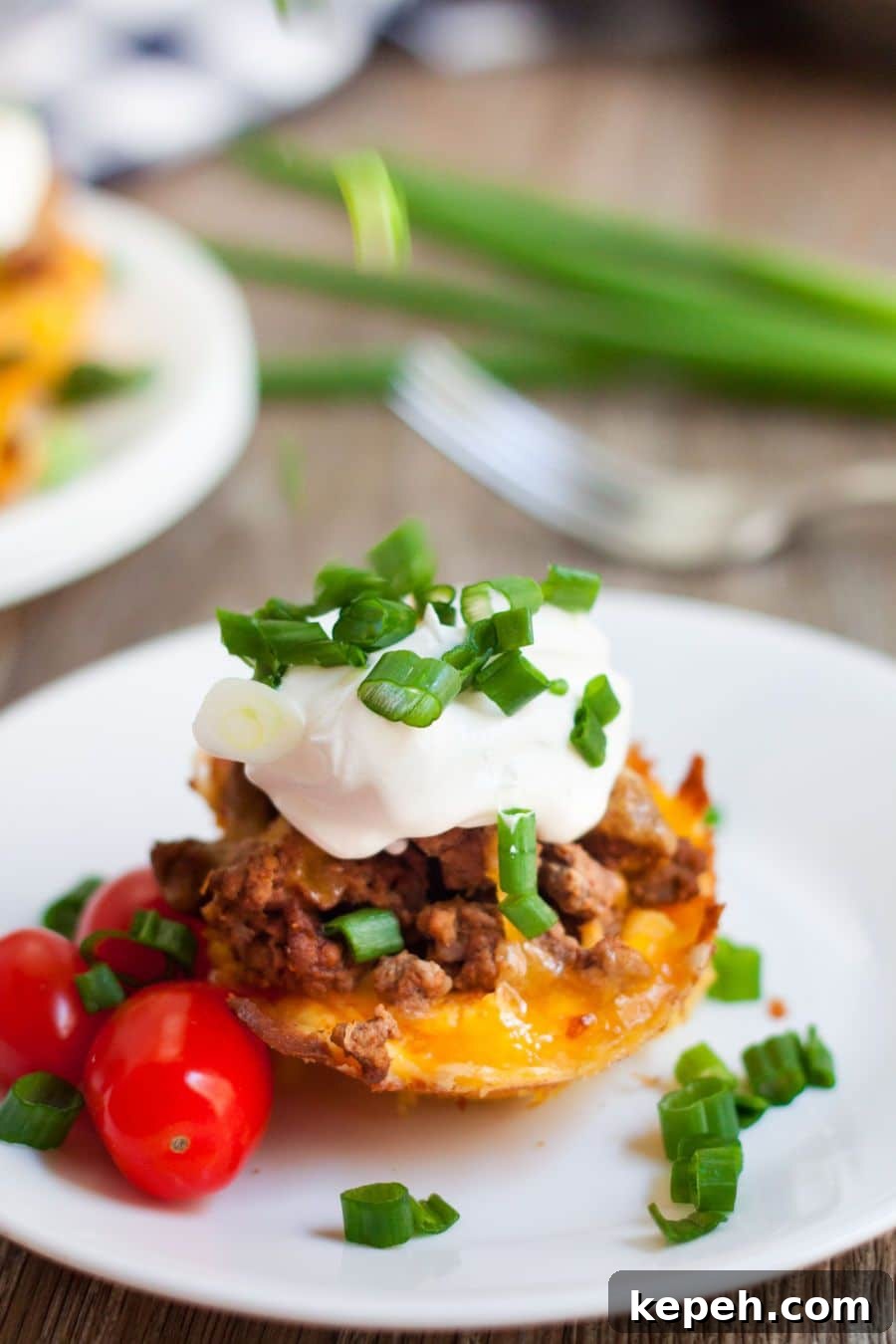 keto taco cups on a white plate topped with sour cream and chives