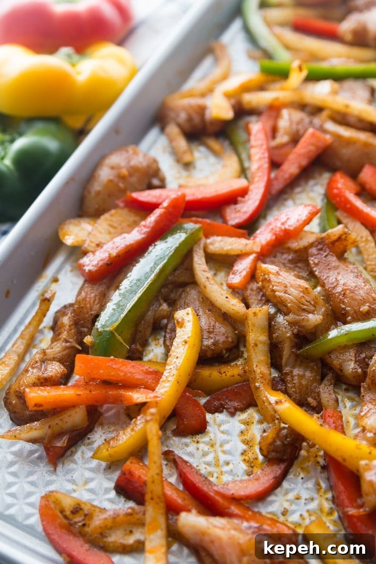 seasoned chicken fajitas and peppers on a sheet pan