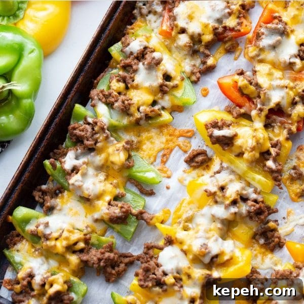 green, red and yellow bell peppers stuffed with ground beef and cheese on a baking sheet