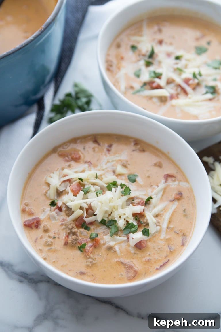 keto taco soup topped with white cheese in two white bowls