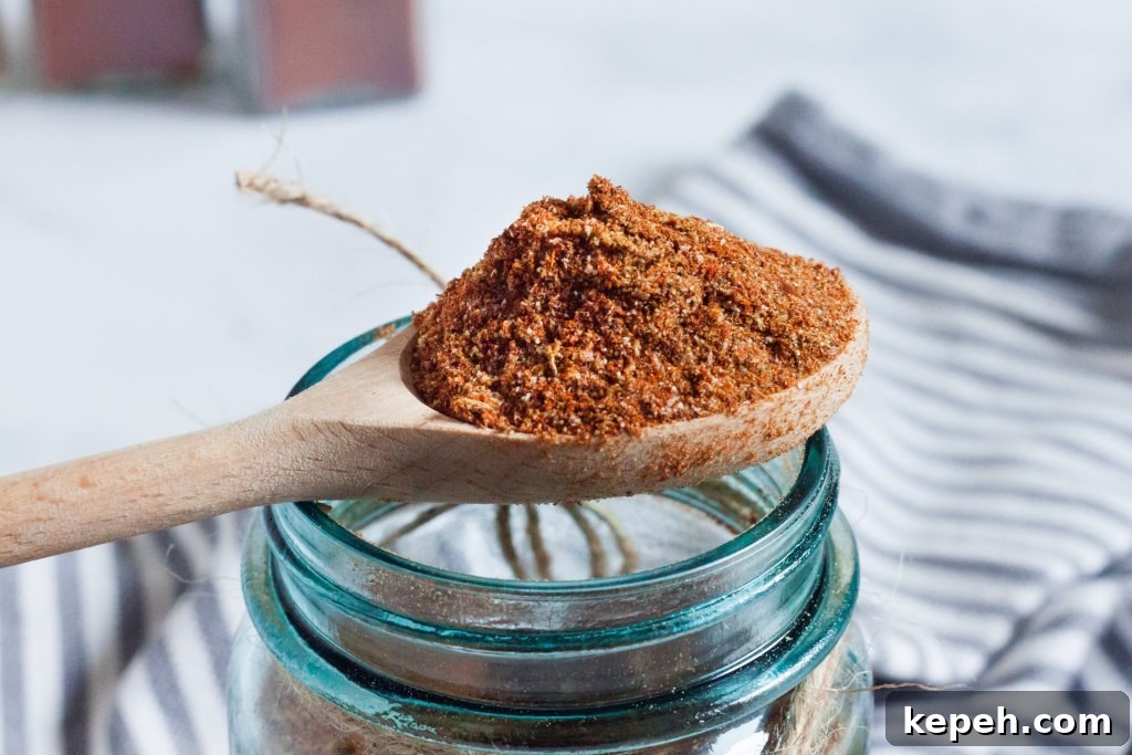 keto taco seasoning in a large wooden spoon sitting over glass jar