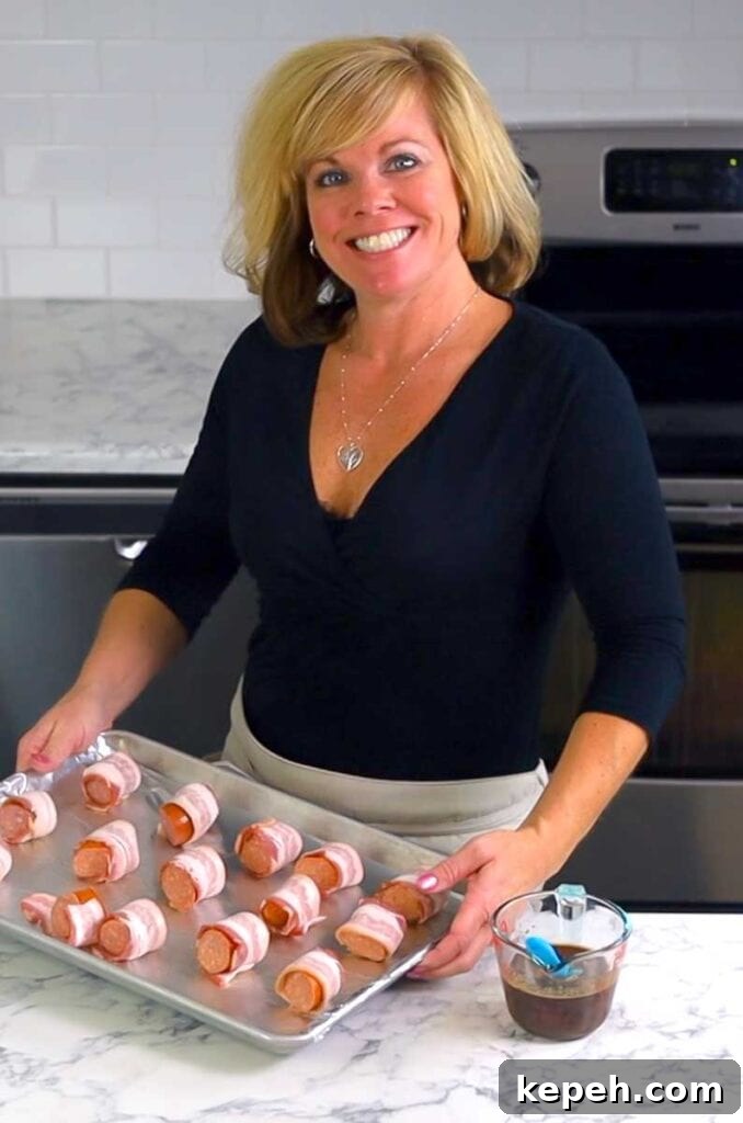 Bourbon Brown Sugar Bacon-Wrapped Sausages Recipe 6 Jennifer holding a baking sheet of bacon wrapped sausages
