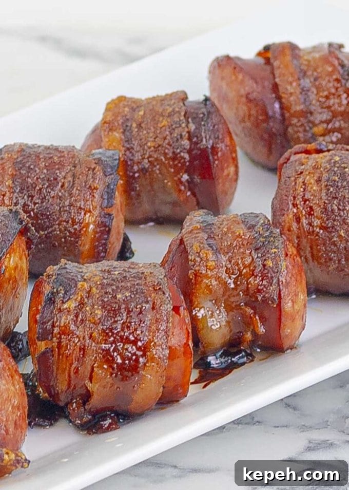 Bourbon Brown Sugar Bacon-Wrapped Sausages Recipe 7 close upBourbon Brown Sugar Bacon Wrapped Sausages on white plate