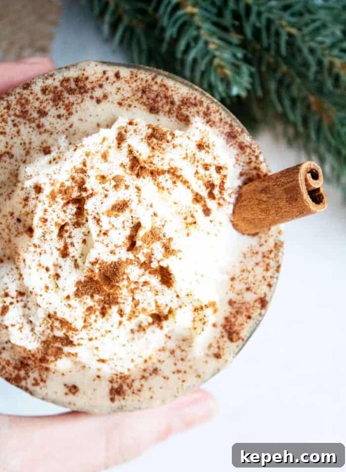 Keto Snickerdoodle Cookies: Low-Carb Cinnamon Treats 8 hand holding a glass of keto eggnog next to greenery