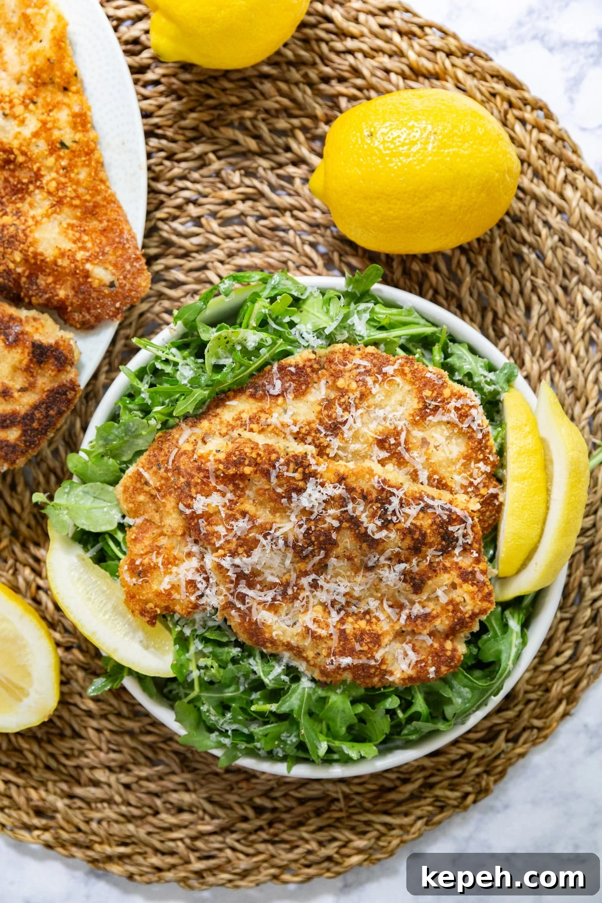 Veal Scallopini with Lemon Butter Sauce Recipe 8 An overhead image of scallopini veal on a bed of arugula with lemons.