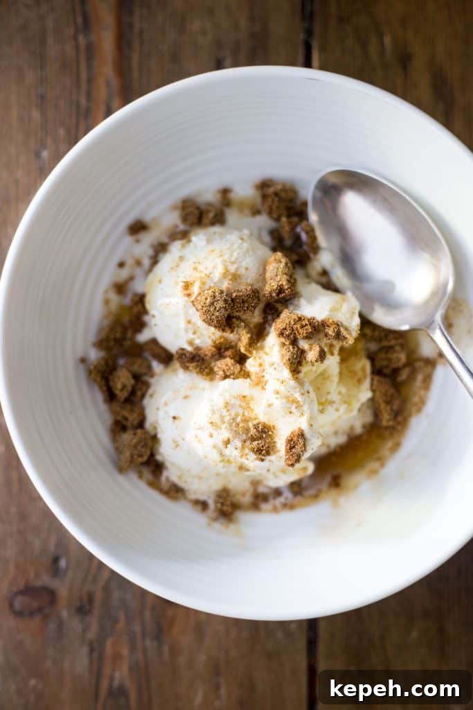 Crispy Ginger Biscuits Without Gluten: Tangy Spice Cookies 10 A white bowl filled with ice cream maple syrup and crushed ginger nuts with a spoon