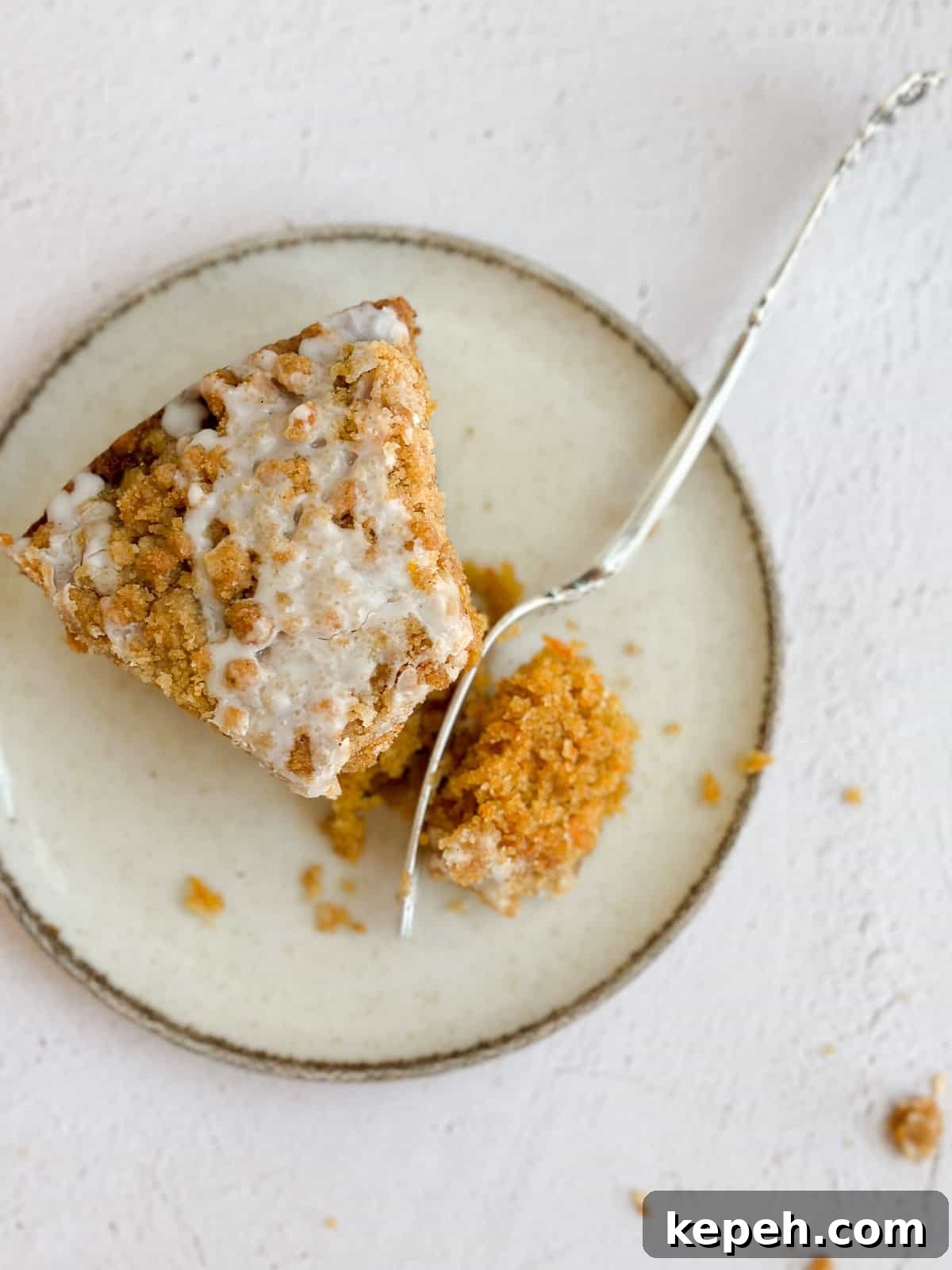 Moist Carrot Coffee Cake with Cream Cheese Glaze 3 a single piece of carrot cake coffee cake on a plate with a fork cutting in.