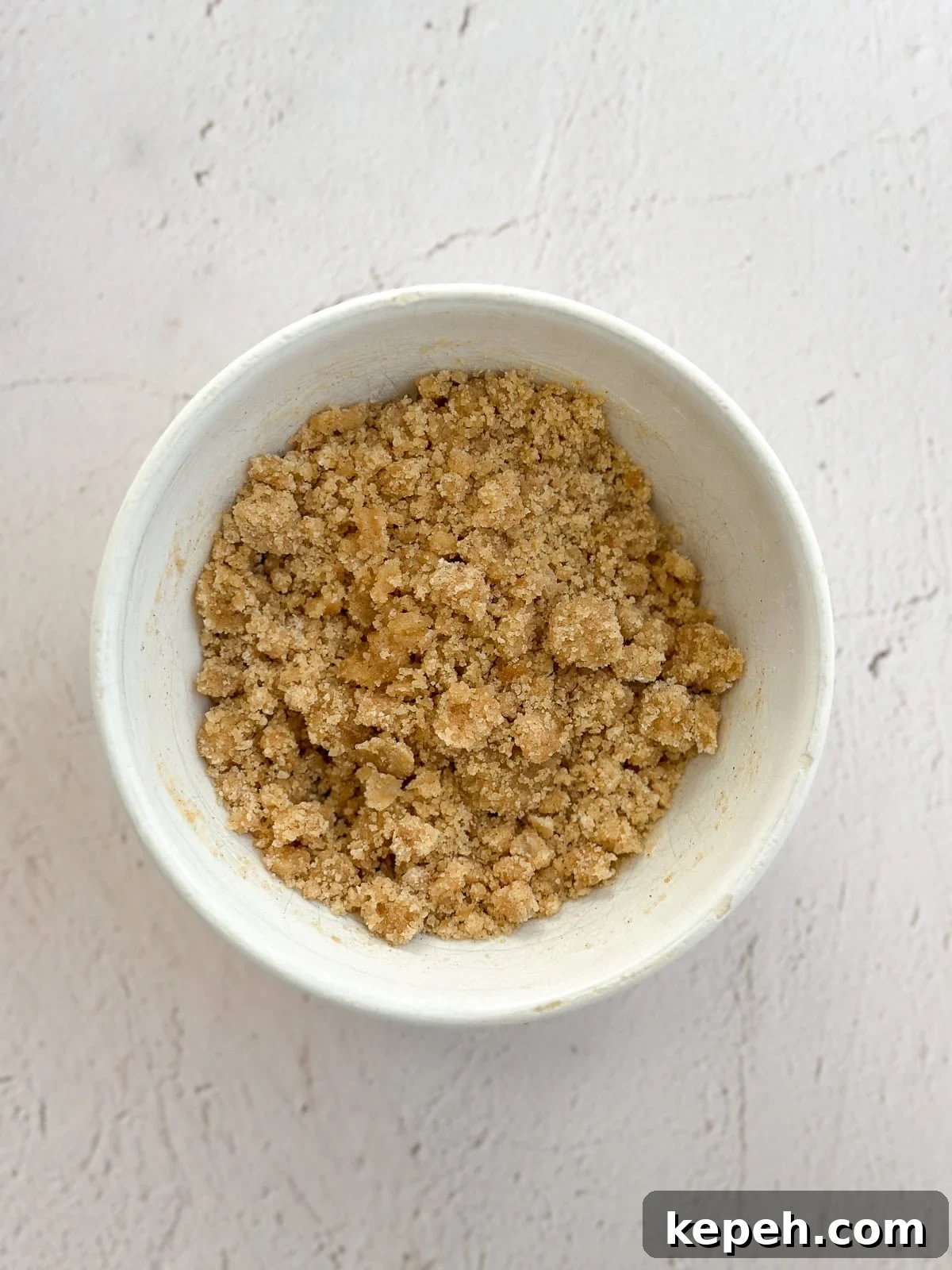 Moist Carrot Coffee Cake with Cream Cheese Glaze 8 crumb topping in a bowl.