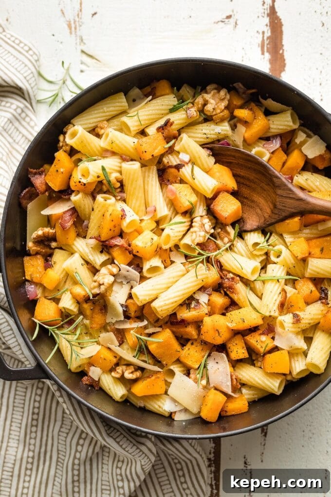 Roasted Butternut Squash Pasta with Sage and Parmesan 8 Wooden spoon lifting out servings of pasta from the skillet.