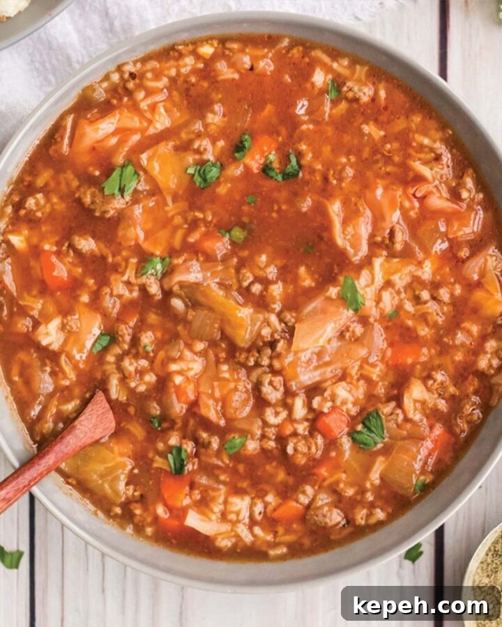 Pot of slow cooker cabbage roll soup served on the table with a wooden spoon.