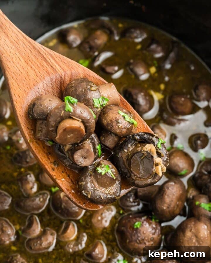 Slow cooker mushrooms with a spoon lifting out a portion.