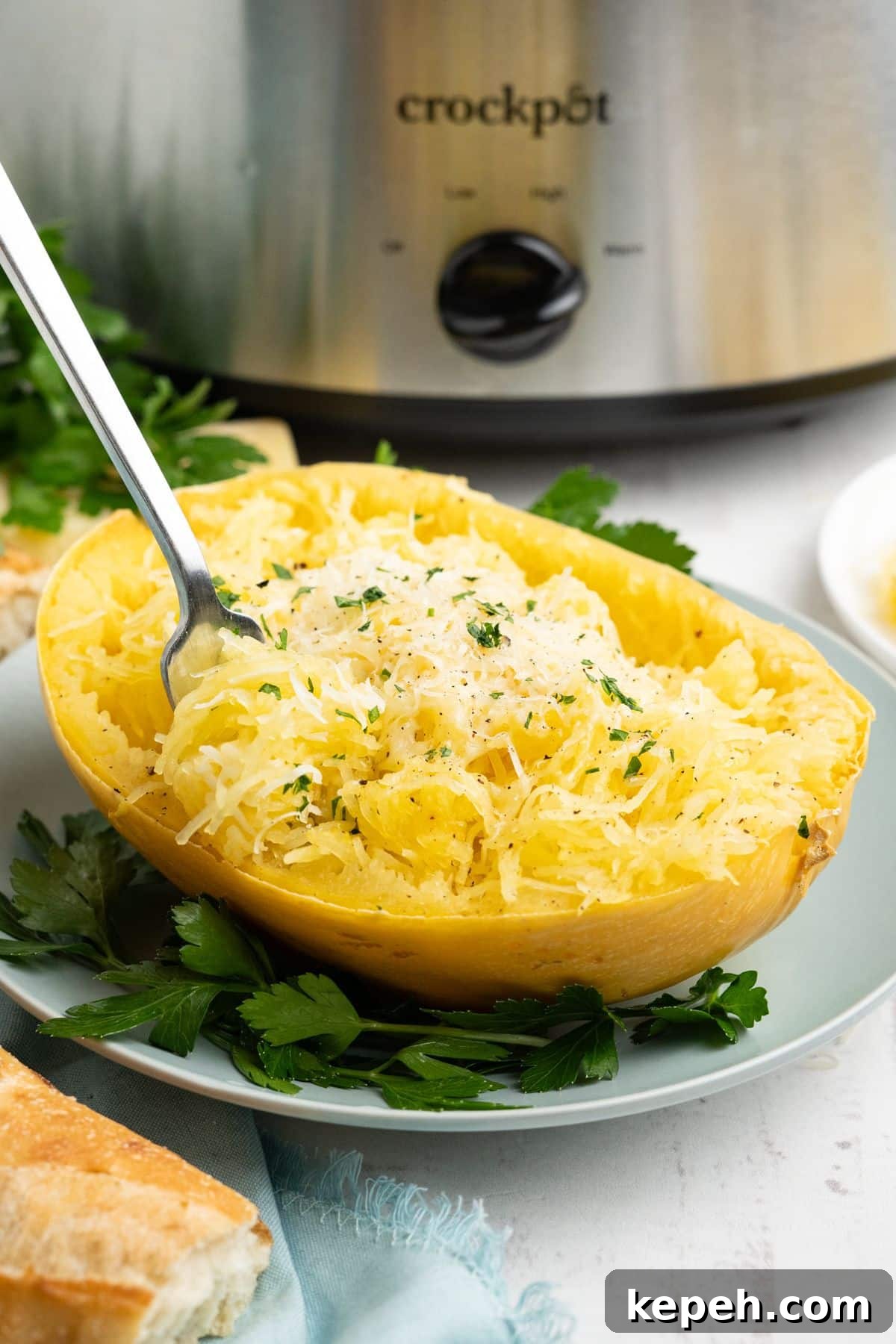 A fork twirling some of the spaghetti squash up with the plate in front of a crockpot.