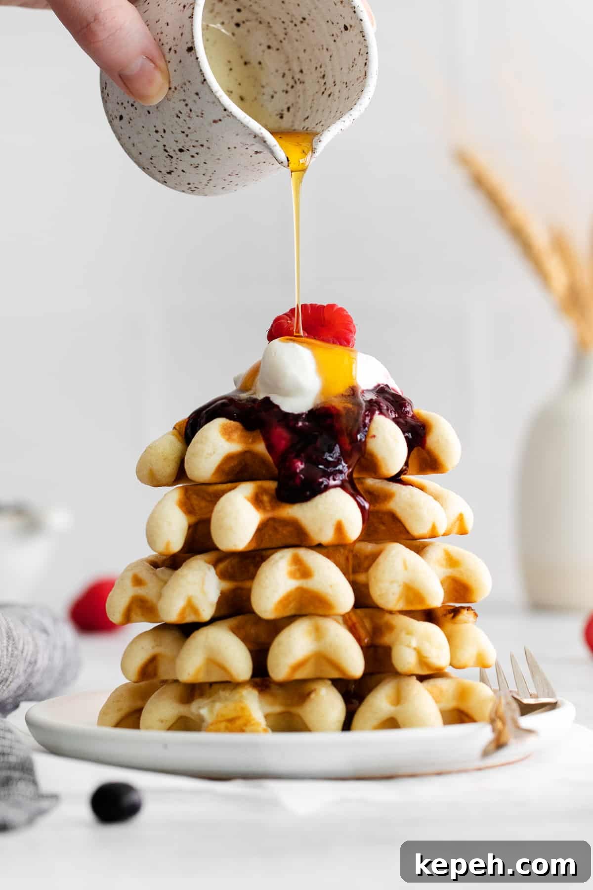 stack of waffles with berry compote and maple syrup.