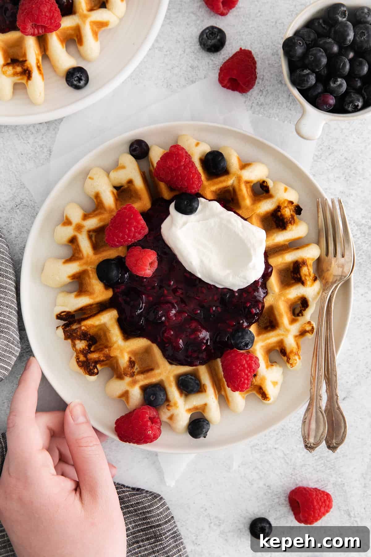 waffle with berry compote and berries on top.
