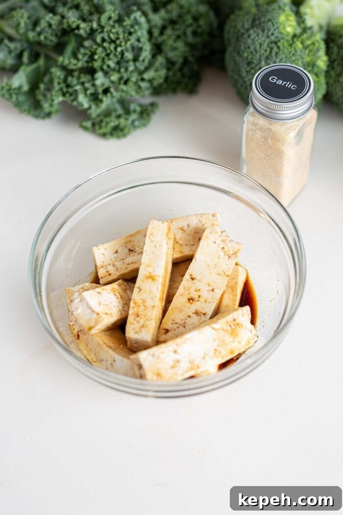 Crispy Tofu and Broccoli Rice Bowl with Sesame-Ginger Sauce 4 Slices of tofu in a small bowl with soy sauce.