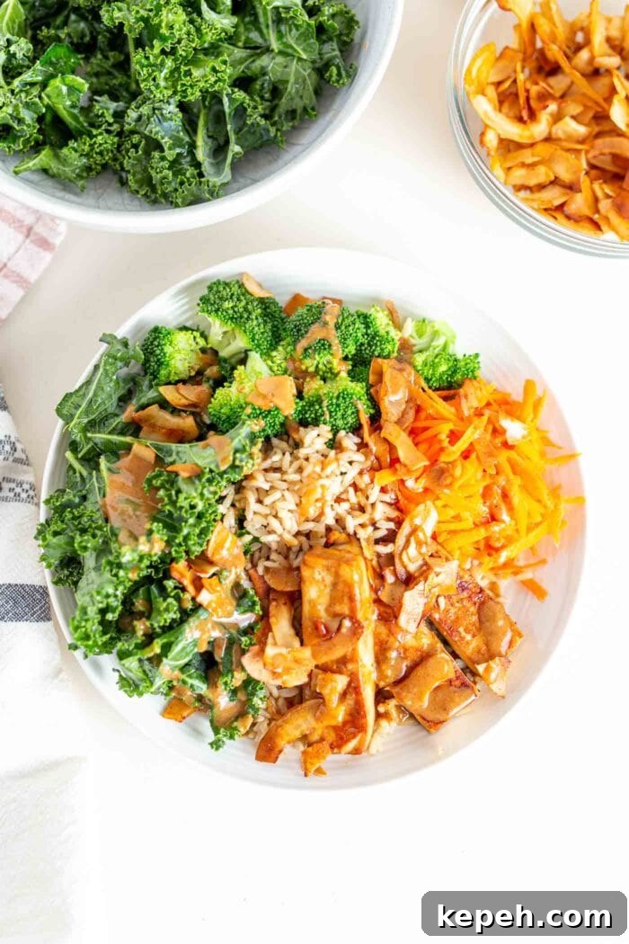 Crispy Tofu and Broccoli Rice Bowl with Sesame-Ginger Sauce 9 A bowl with tofu, sauce, kale, broccoli, carrot and coconut bacon.
