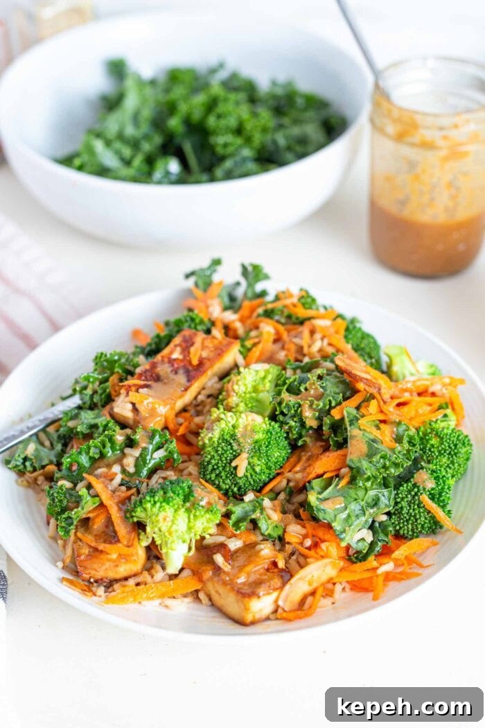 Crispy Tofu and Broccoli Rice Bowl with Sesame-Ginger Sauce 10 A bowl with shredded carrot, broccoli, tofu, kale and a creamy sauce.