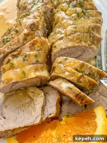 Sliced, boneless pork tenderloin with orange sauce and sliced oranges.