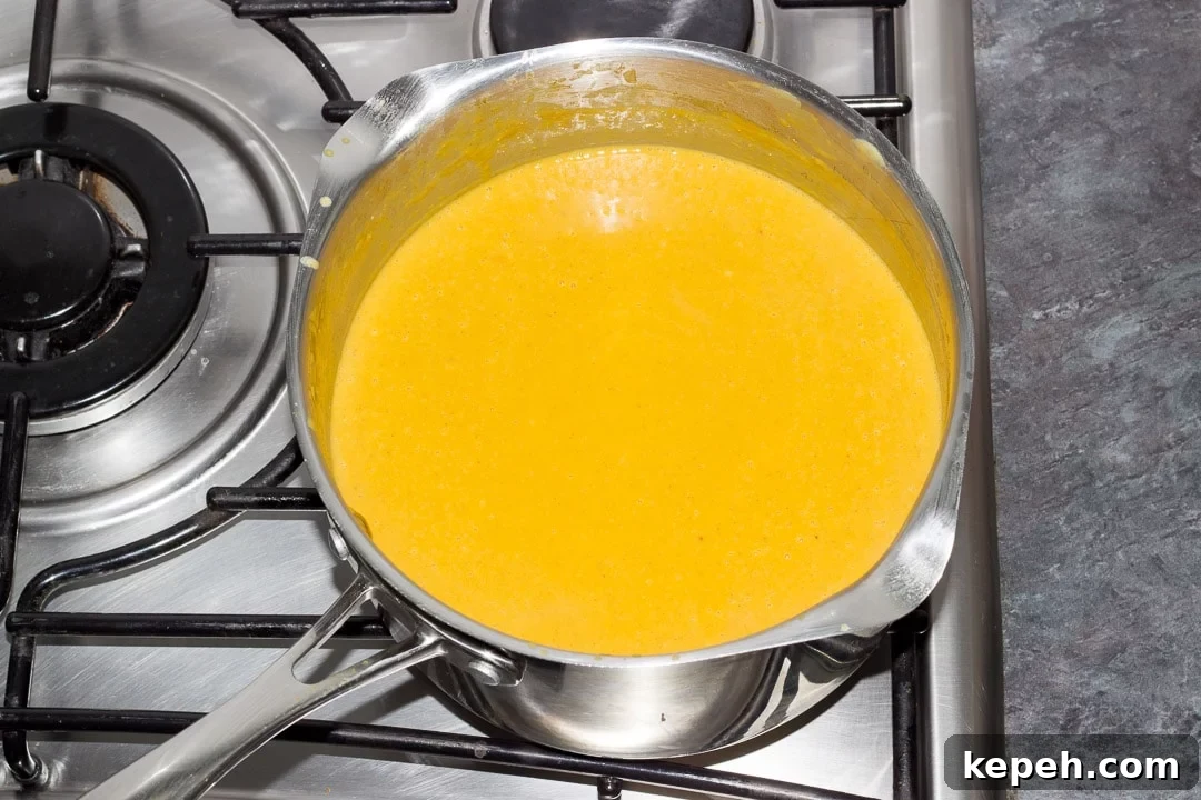 Curried Coconut Lentil Soup with Warm Aromatic Spices 10 pureed curried coconut lentil soup simmering in a large pot on the hob