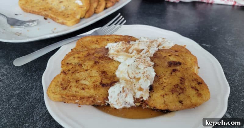 Eggnog French Toast Recipe with Video Tutorial 11 Eggnog French Toast with Eggnog Whipped Cream on a white plate with a silver fork