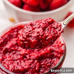 A spoon lifting some raspberry chia jam out of a jar.