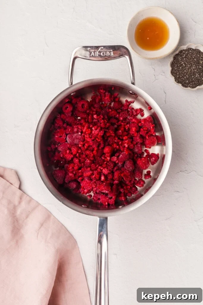 Raspberry Chia Seed Jam Recipe: Quick No-Cook Fruit Spread 2 Frozen raspberries and lemon juice in a saucepan next to some honey and chia seeds.