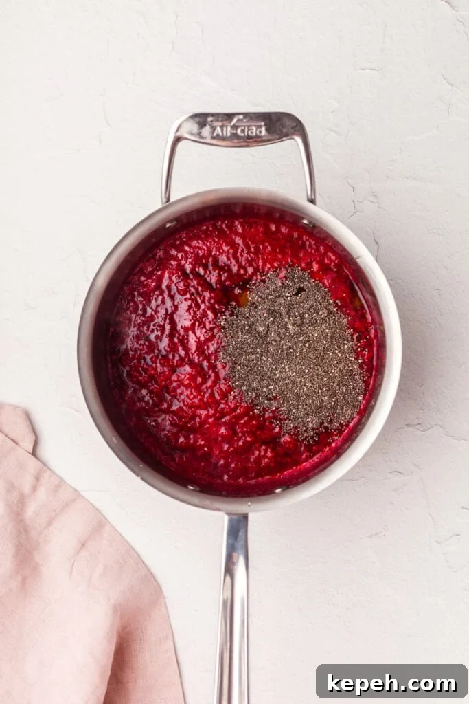 Raspberry Chia Seed Jam Recipe: Quick No-Cook Fruit Spread 4 Adding honey and chia seeds to a saucepan with cooked down raspberries.