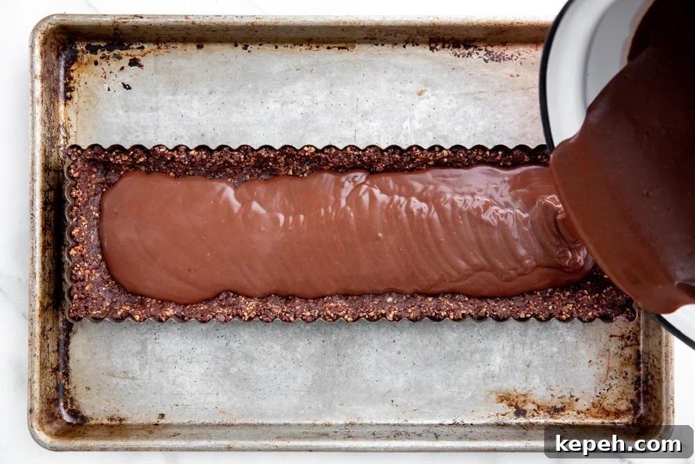 Process shot showing how to pour the chocolate pudding in the vegan date nut crust.