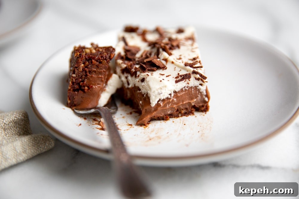 A half eaten piece of chocolate tart on a plate with a fork.