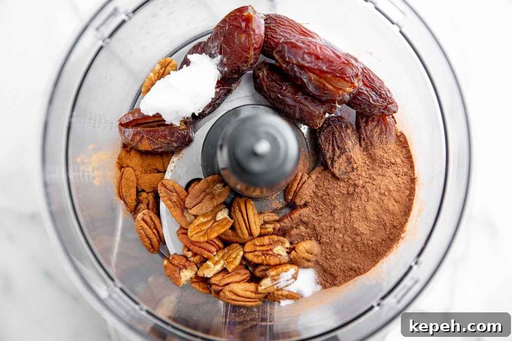 Process shot showing the ingredients for the date nut crust in a food processor.